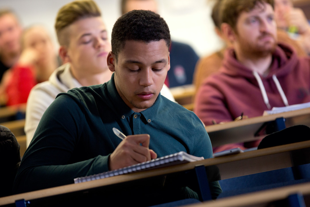 Student writing notes in a class