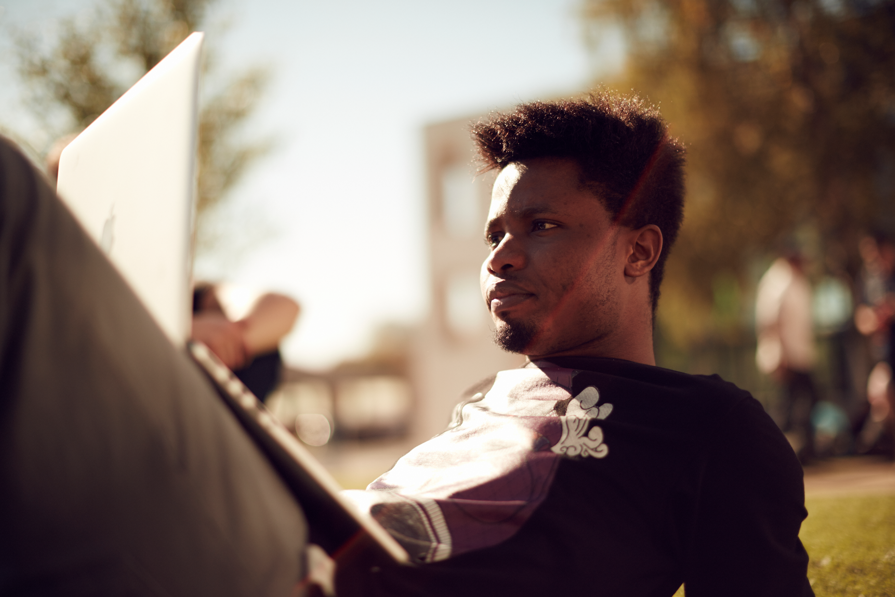 International student sat on the grass with a laptop