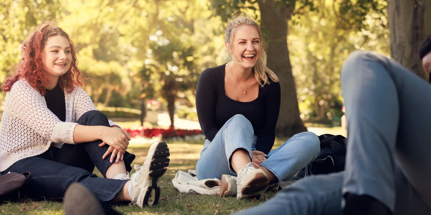 Students sitting on the grass laughing